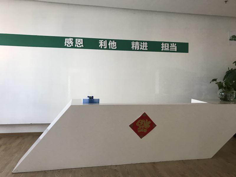 图为铅笔头公司前台，陈耀辉说突出“感恩、利他、精进、担当”这八个字更重要，因此他把公司的logo做成小小个放在右上角。